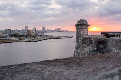 City by sea against cloudy sky seen from fort during sunset