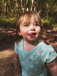 Cute baby girl standing in forest