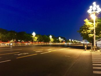 Illuminated city street against clear sky at night