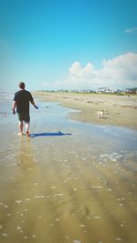 Rear view of man walking on shore at beach