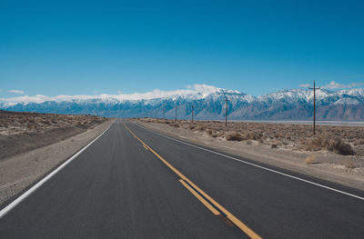 Road by mountains against clear blue sky