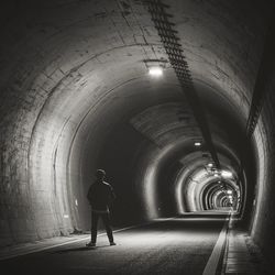 Rear view of man walking in illuminated tunnel