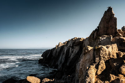 Rock formation on beach against clear sky