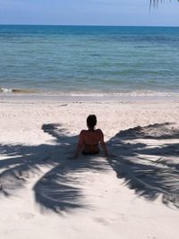 Rear view of woman sitting at beach