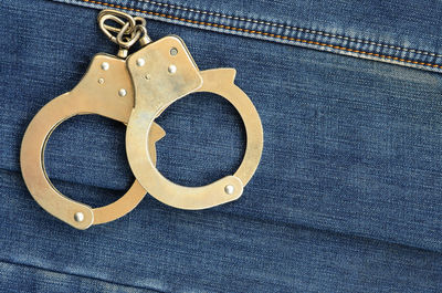 High angle view of handcuffs on denim