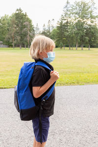 Child in mask carrying backpack, going to school. back to school concept after reopening. 