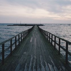 Pier on sea against cloudy sky