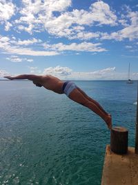 Full length of man diving in sea against blue sky