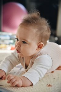 Portrait of cute baby girl lying on bed at home