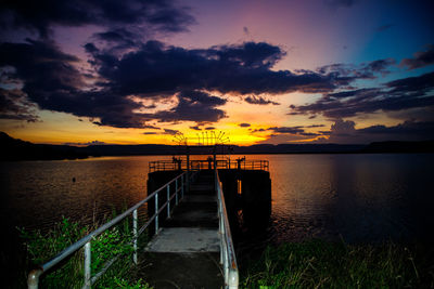 Pier over sea against sky during sunset