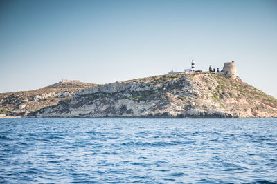 Lighthouse by sea against clear sky