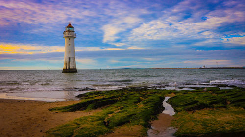 Lighthouse by sea against sky