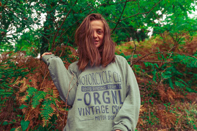 Portrait of woman standing against trees