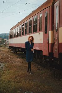 Full length of young woman standing on train at railroad station