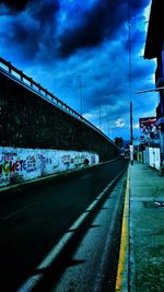 Road by illuminated bridge against sky