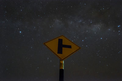 Low angle view of road sign against sky at night