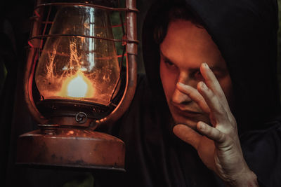 Close-up of man touching lantern at night