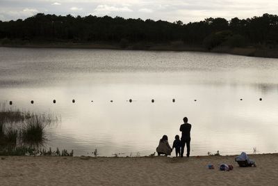 Rear view of family standing at lakeshore