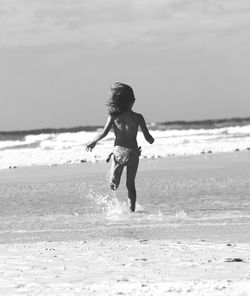 Rear view of girl running towards sea at beach