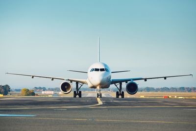 Airplane on runway against clear sky