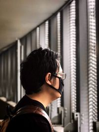 Rear view of young man looking through window