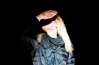 Woman wearing hat standing against black background