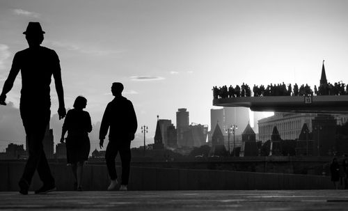 Silhouette of people standing on riverbank
