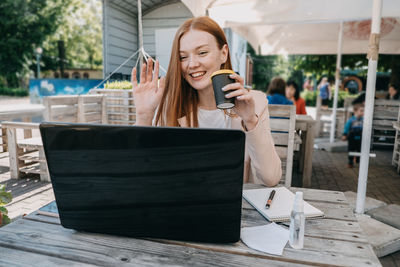 Working, outdoors, remote work. redhead business woman drinking coffee and working on the laptop