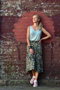 Portrait of a woman standing against brick wall