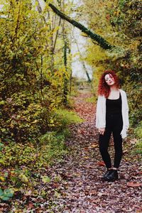 Full length of woman standing by tree during autumn