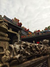 Low angle view of statue in temple against cloudy sky