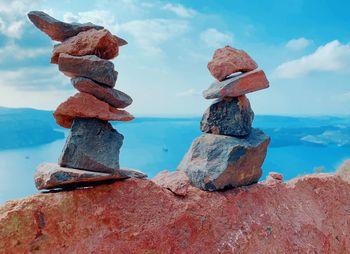 Stack of rocks by sea against sky