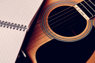 High angle view of spiral notebook on guitar