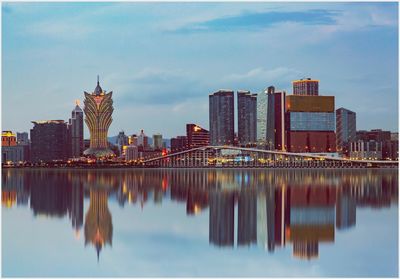 Reflection of buildings in river against sky