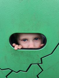 Portrait of boy peeking through hole