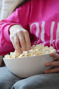 Midsection of woman having popcorn at home