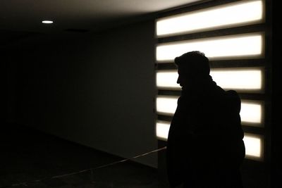 Rear view of silhouette man standing by railing