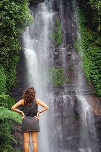 Rear view of woman standing against waterfall