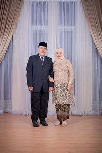 Full length of couple standing against wall