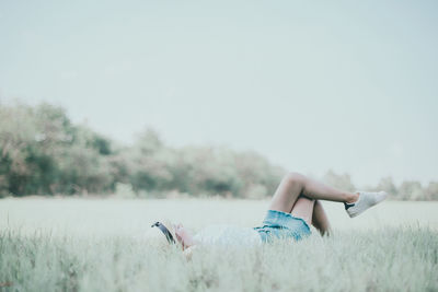 Young woman lying on grassy field at public park