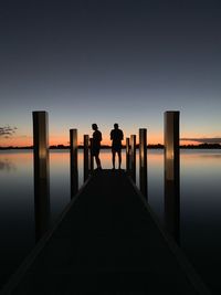 Rear view of silhouette man standing on sea against sky during sunset