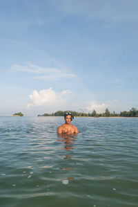 Shirtless man in sea against sky