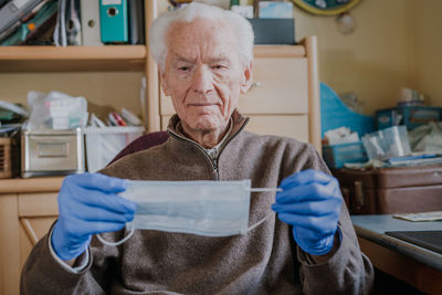 Portrait of man holding mask at home