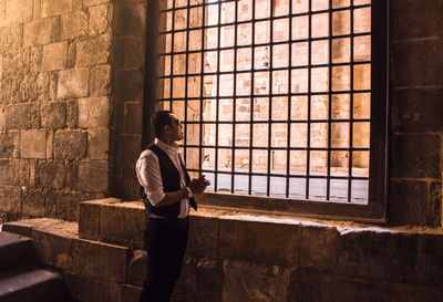 Side view of man standing window in historic building 