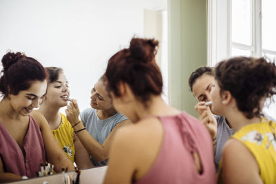 Cheerful diverse women doing makeup together at home