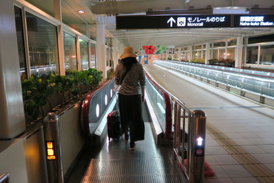 Rear view of woman walking on illuminated railway station