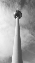 Low angle view of communications tower against cloudy sky