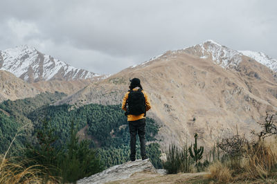 Rear view of man looking at mountains against sky