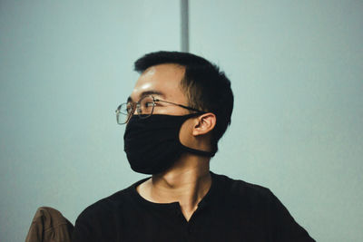 Portrait of young man looking away against wall