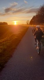 Bicycle on road by field against sky during sunset